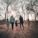 A family holding hands and walking along a bare path during a winter day, emphasizing unity and togetherness.