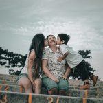 Happy family sitting on bleachers, capturing a loving moment outdoors in Guayaquil.